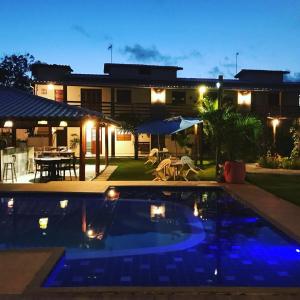une piscine devant une maison la nuit dans l'établissement Village quinta da Alegria- Itacimirim, à Camassari
