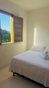 une chambre avec un lit blanc et une fenêtre dans l'établissement Village quinta da Alegria- Itacimirim, à Camassari