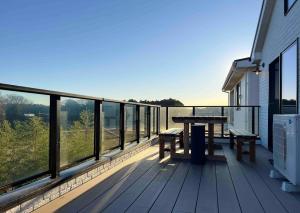 una terraza de madera con mesa y bancos. en The Mansion 19 Modern Comfort with Serene Rice Field Views, en Inzai