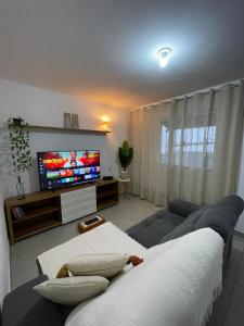 a living room with a couch and a flat screen tv at Quase um Spa in Petrópolis