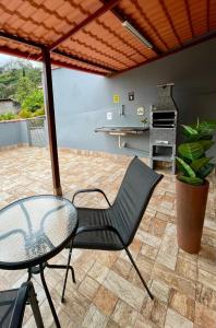 a patio with a glass table and a chair at Quase um Spa in Petrópolis +28 photos