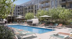 Una piscina con sillas y sombrillas frente a un edificio. en Lux 2BR w Gym Pool sleep 6 in Assembly Square, en Winter Hill