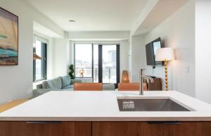 Una cocina con fregadero y una sala de estar. en Lux 2BR w Gym Pool sleep 6 in Assembly Square, en Winter Hill 35 fotos más