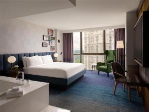 a hotel room with a bed and a green chair at The Starling Atlanta Midtown, Curio Collection by Hilton in Atlanta
