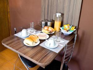 une table en bois avec des assiettes de nourriture dans l'établissement HOTEL Don Carlo, à São Bernardo do Campo