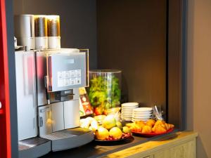 a counter with a refrigerator with bowls of fruit on it at ibis Köln Messe in Cologne +56 photos