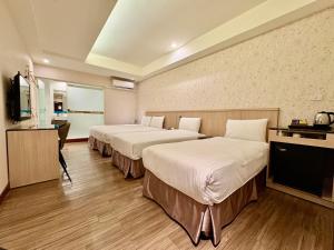 Una habitación de hotel con dos camas y un televisor. en Tc慢旅花蓮館-近東大門夜市市中心, en Hualien City