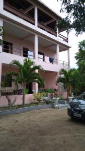a pink building with palm trees in front of it at Pousadinha Mangabeiras II in São Mateus