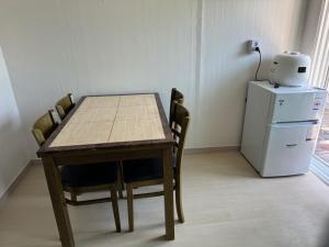 a dining room table with chairs and a refrigerator at Gangneung Sandstay in Ŭmji-mal