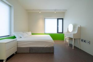 une chambre avec un lit, un bureau et un miroir dans l'établissement Gangneung Stayharam Villa, à Kyŏngp'o-mal 3 autres photos