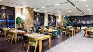 a restaurant with tables and chairs and windows at Golden Tulip Ever Yongin Hotel in Tugyeul