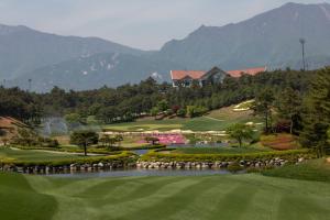 a view of a golf course with mountains in the background at Pine Ridge Resort in Goseong