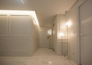 a hallway with white walls and a door and lights at Jinhae Yongwon Londoner Business Hotel in Yongjae