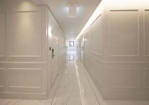 a hallway with white walls and white floors and doors at Jinhae Yongwon Londoner Business Hotel in Yongjae