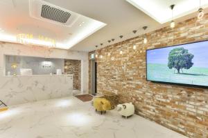 a living room with a tv on a brick wall at Wonju Hotel Raum in Wonju