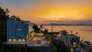 a large building with a sunset in the background at Yeosu Road 328 Ocean View Pool Villa in P'yongsa-ri