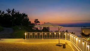 a fence with lights and an umbrella on a beach at Yeosu Road 328 Ocean View Pool Villa in P'yongsa-ri