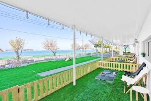 a porch with a green yard with chairs and tables at Glamdog Dog Pension Yeongheungdo Branch in Pŏdŏni