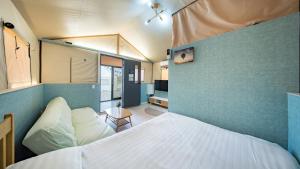 a bedroom with a bed and a blue wall at Gangneung Base Camp Caravan Glamping in Hwapyeong-dong