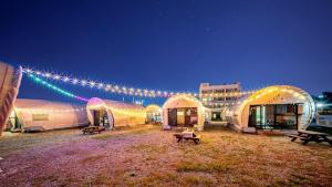 a group of tents in a field with lights at Gangneung Base Camp Caravan Glamping in Hwapyeong-dong +4 photos