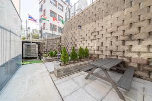 un banco de madera sentado en un patio junto a una pared de ladrillo en Gapyeong The Cozy Pool Villa, en Piryŏngtŏ-ri