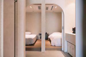 ein Schlafzimmer mit zwei Betten und einem Spiegel in der Unterkunft Cinnamon Stay Gwangan in Millak-tong