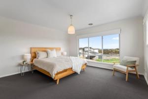 a bedroom with a bed and a window and a chair at 4BR Torquay Retreat with Serene Views in Torquay