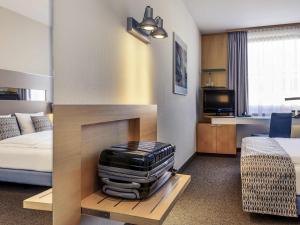 a hotel room with a bed and a suitcase on a table at Sunday Hotel Düsseldorf City Nord in Düsseldorf +64 photos