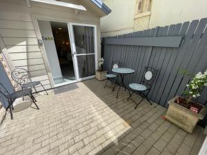 Un patio con sillas y mesas y una valla. en Salty Kisses, en Narrabeen