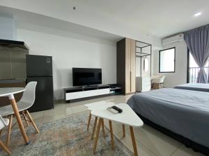 Un dormitorio con una cama, un televisor y una mesa. en Alinea BlueView Suites, en Shah Alam