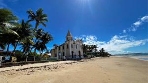 een wit gebouw op het strand met palmbomen bij Mar de Campas - Tamandaré 016 in Tamandaré