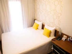 a bedroom with a bed with yellow pillows and a window at Mercure Sao Caetano do Sul in São Caetano do Sul +63 photos