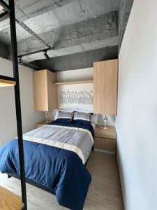 a bedroom with a bed with blue sheets and wooden cabinets at Apartamento excelente ubicacion in Sogamoso