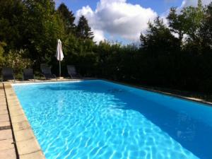 una gran piscina azul con sombrilla en Charmant Gîte avec Cheminée et Animaux Admis - FR-1-496-31, en Saint-Haon-le-Vieux