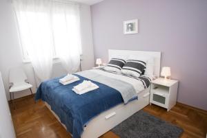 a white bedroom with a large bed with a blue blanket at Paw Rooms in Zagreb