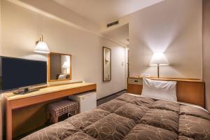 a hotel room with a bed and a desk with a television at Az Inn Fukui (Ace Inn Fukui) in Fukui +32 photos