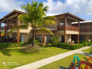 a house with a palm tree in front of it at Reserva itacimirim, condomínio eco itacimirim in Camacari
