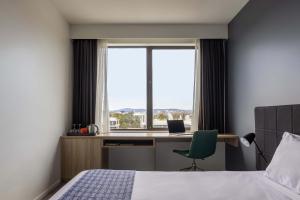 Un dormitorio con una cama y un escritorio y una ventana. en Mantra MacArthur Hotel, en Canberra 142 fotos más