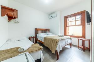 a room with two beds and a window at Pousada Maré Cheia in Paraty