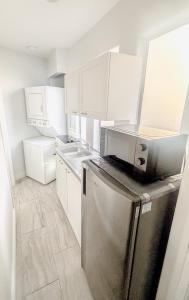 una cocina con nevera de acero inoxidable y armarios blancos en Civic Centre, Compact Ste layout & Separate Entry, en Gilbert