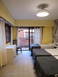 a room with three beds in a room with a window at Kairos in Buenos Aires