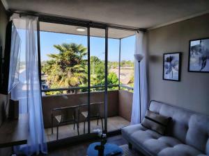 a living room with a couch and a large window at Departamento en Talca con 3D-2B y estacionamiento in Talca