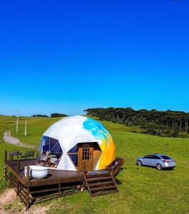 a large dome tent in a field with a car at Glamping Atmosphera in Cambará