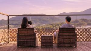 a group of people sitting on a deck watching the mountains at Gapyeong Pinetree Kids Pool Villa in Gapyeong
