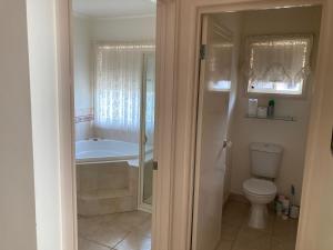 a bathroom with a tub and a sink and a toilet at Home Stay on High Room 1 Queen Bed and Room 2 King Bed OR Two Single Beds in Swan Hill +5 photos