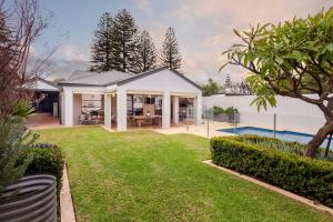 a white house with a yard and a pool at Henley Beach House - Luxury by the Sea in Henley Beach