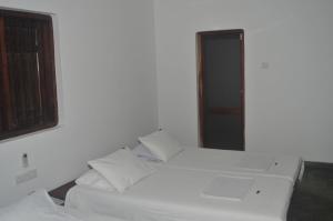 two white beds in a room with a window at Panthera Lodge Yala in Kirinda