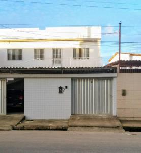 a white building with two garage doors on a street at Casa 6 in Olinda