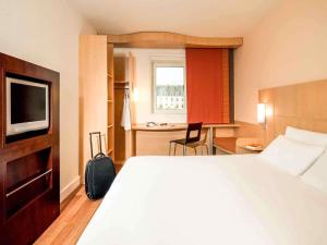 una habitación de hotel con una cama y un televisor en Ibis Vitré Centre, en Vitré