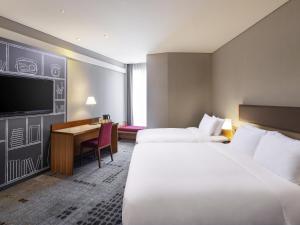 a hotel room with two beds and a desk at Ibis Ambassador Myeongdong in Seoul